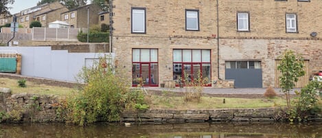 A stone building with multiple windows and a door, situated next to a body of water.