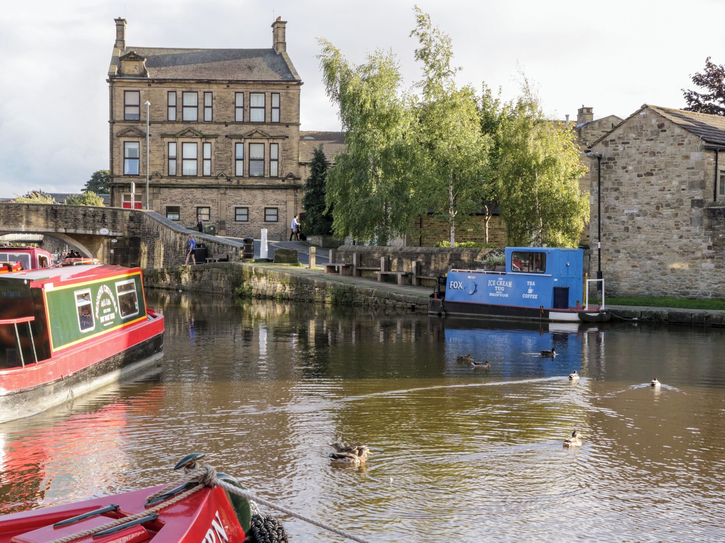 A canal with boats, a bridge, and buildings in the background.