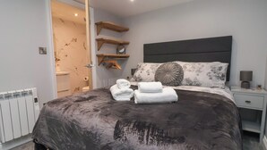 Une chambre moderne avec un grand lit, une tête de lit en bois et des étagères intégrées.