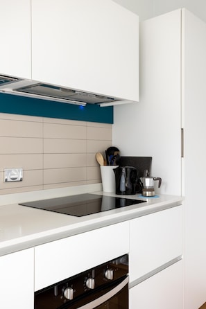 A modern kitchen with a white countertop, black stove, and a blue backsplash.