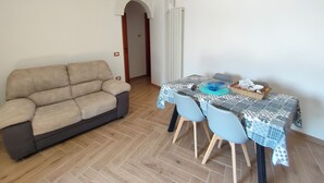 A living room with a beige sofa, a dining table with chairs, and a patterned tablecloth. - Il Trullo di Antonio (Martina Franca)