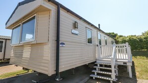 A mobile home with a front porch and a staircase leading to the entrance. - 13 Sunset Terrace Rockley Park (Poole)