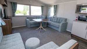 A compact living space with a sofa set, a small table, and a microwave. - 13 Sunset Terrace Rockley Park (Poole)