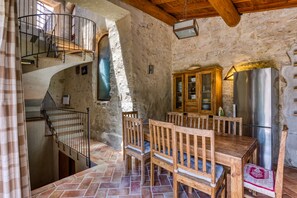 A rustic stone interior with a wooden dining table, chairs, a staircase, and a stainless steel refrigerator. - Holiday Home 'La Tour' with Shared Pool, Private Terrace and Wi-Fi (Notre-Dame-de-Londres)