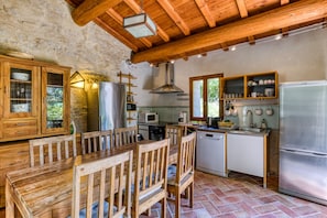 A rustic kitchen with wooden furniture, a stone wall, and a modern refrigerator. - Holiday Home 'La Tour' with Shared Pool, Private Terrace and Wi-Fi (Notre-Dame-de-Londres)