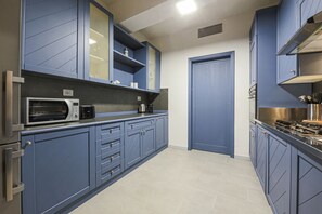 A modern kitchen with blue cabinetry, a microwave, a coffee maker, and a stove. - Apartments Florence - Living in Oltrarno (Firenze)