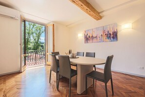 A dining area with a round table, six chairs, and a view through glass doors to an outdoor balcony. - Apartments Florence - Living in Oltrarno (Firenze)