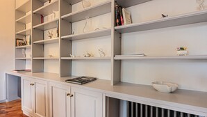 Une cuisine moderne et blanche, dotée d’étagères et de placards intégrés, d’un plan de travail et d’un radiateur.