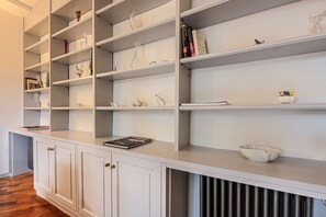 A white, modern kitchen with built-in shelves and cabinets, a countertop, and a radiator.