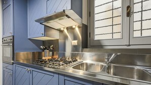 Une cuisine moderne avec des armoires bleues, des appareils en acier inoxydable et une grande fenêtre à carreaux.
