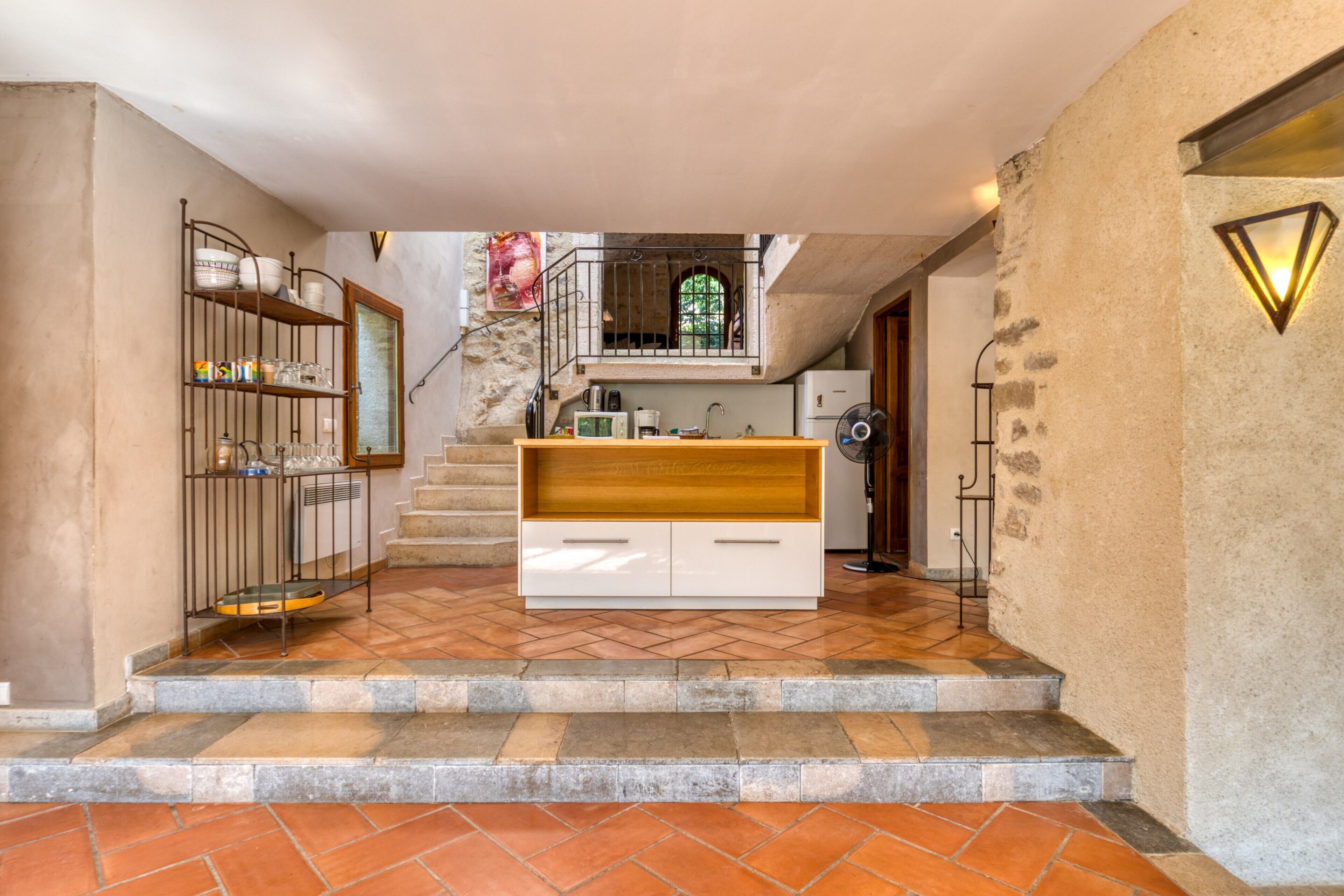 A kitchen with a wooden countertop, a white cabinet, and a staircase leading to an upper level.