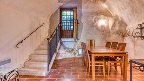 A rustic interior with a staircase, a dining table with chairs, and a view through a window. - Holiday Home 'Mas Grand Bosc' with Shared Pool, Private Terrace and Wi-Fi (Notre-Dame-de-Londres)