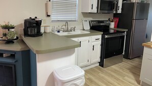 Una cocina moderna con armarios blancos, electrodomésticos de acero inoxidable, una cafetera y un fregadero.
