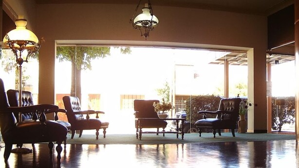 A lobby with a reception desk, several chairs, and a large window providing a view of the outdoors. - Acapulco (Necochea)