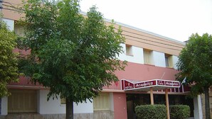 A hotel named Acapulco with a red and white sign, a tree in front, and a yellow curb. - Acapulco (Necochea)