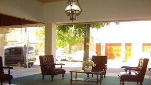 A spacious lobby with a large window, a chandelier, and two armchairs with a small table in the center. - Acapulco (Necochea)