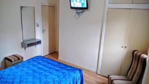 A bedroom with a bed, a chair, a TV, and a wardrobe. - Acapulco (Necochea)