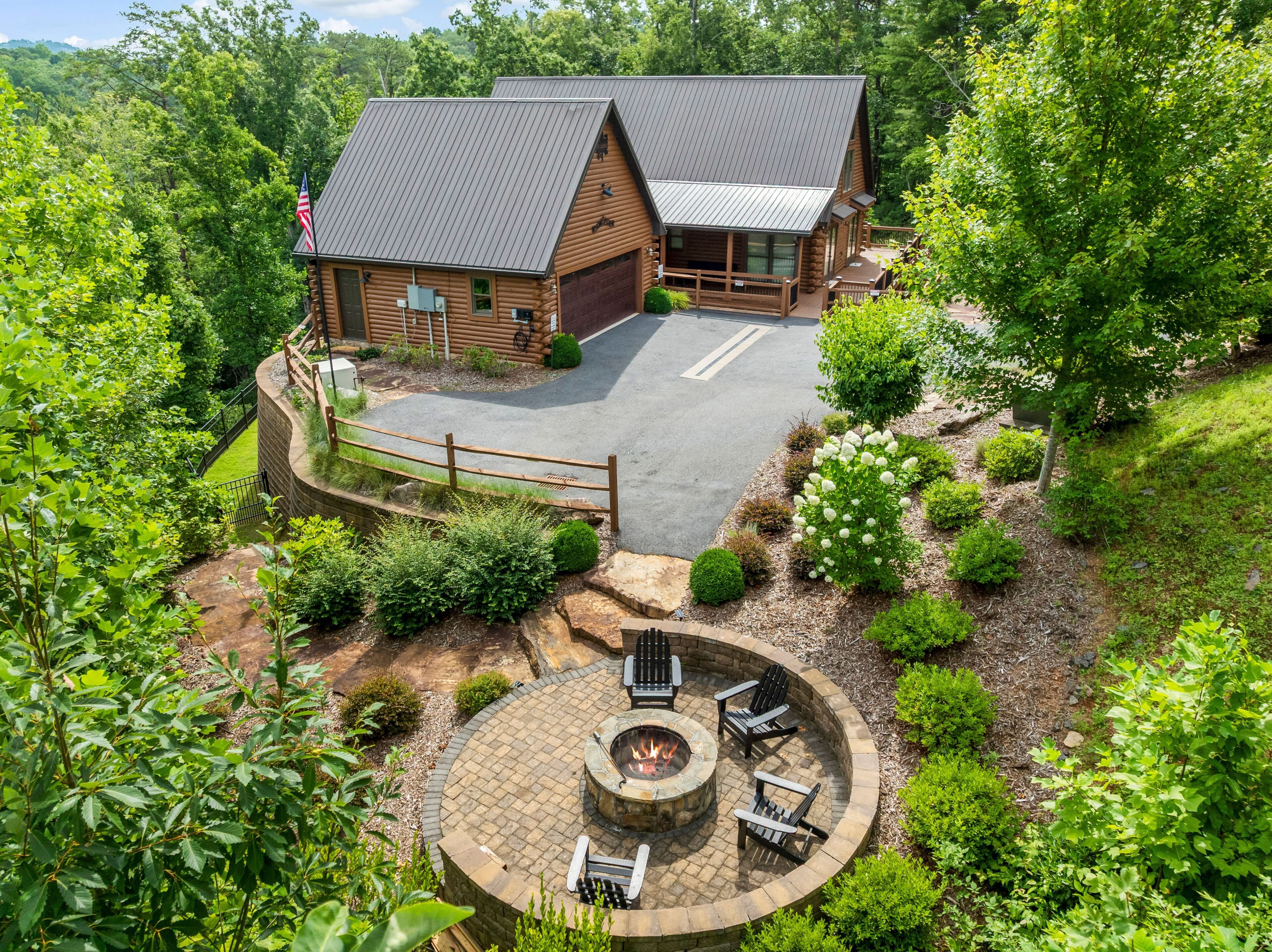 A log cabin with a fire pit and outdoor seating, surrounded by lush greenery.
