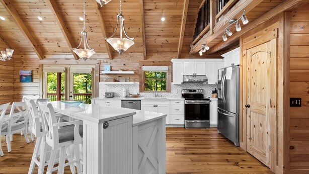 Une cuisine spacieuse, dotée de meubles en bois, d’un îlot central et d’appareils électroménagers modernes.