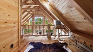 Un intérieur en bois avec un plafond incliné, une vue sur l’extérieur et un radiateur fixé au mur.