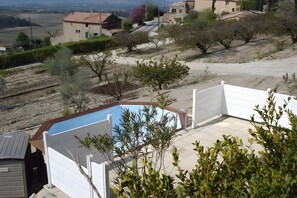 En boligejendom med swimmingpool, overdækket terrasse og udsigt til et kuperet landskab.