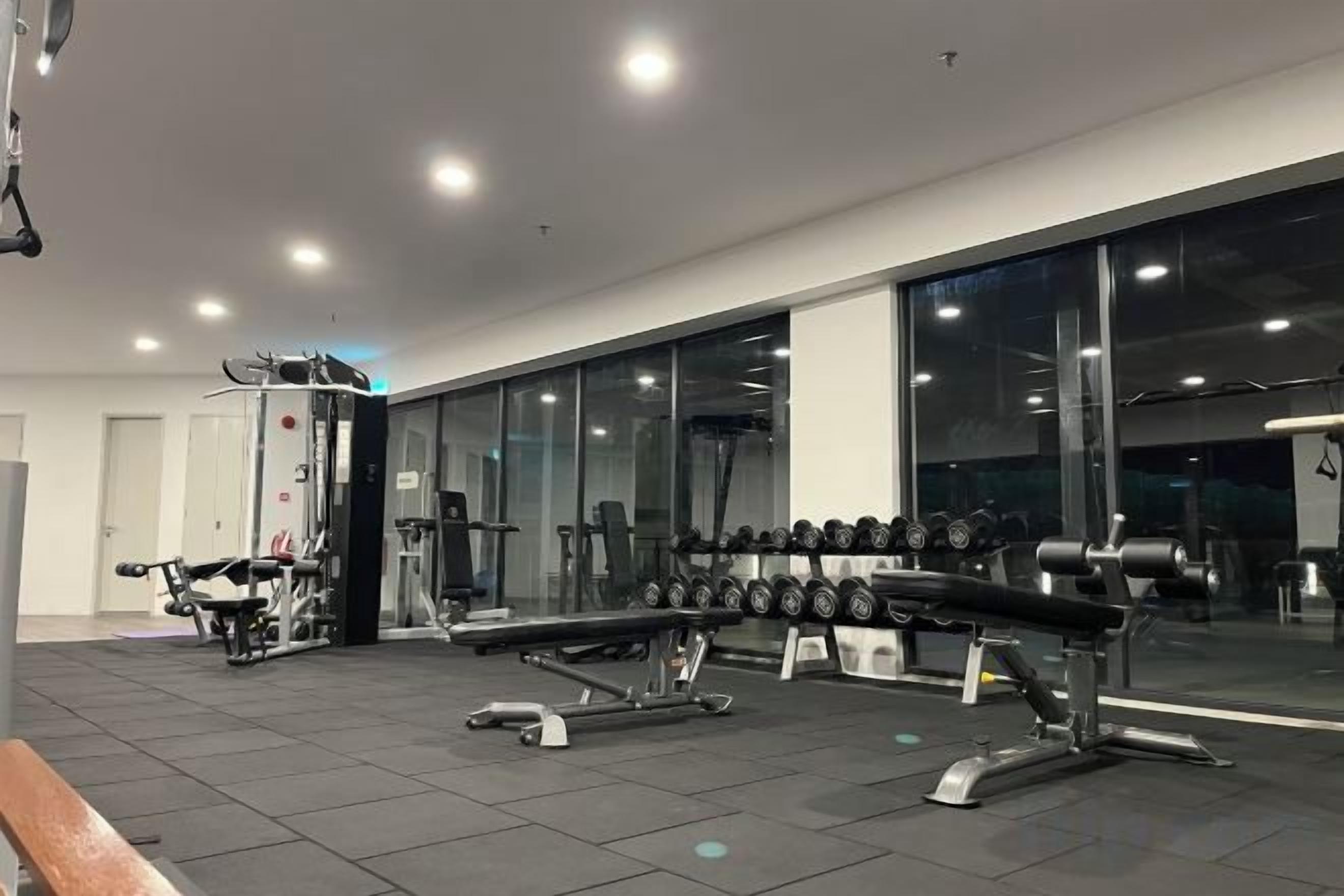 A gym with exercise equipment, large windows, and a mirror.