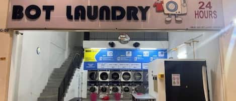 Un cuarto de lavandería con un cartel que indica servicio las 24 horas.