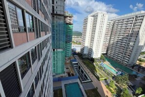 Un edificio de gran altura con varios pisos, una piscina y una zona ajardinada.
