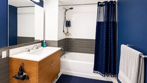 Een moderne badkamer met een houten wastafelmeubel, een bad en een douchehoek.