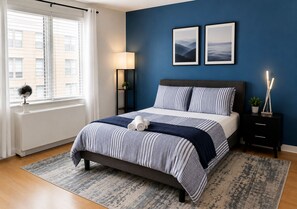 A bedroom with a bed, a nightstand, a lamp, a globe, and two framed pictures on the wall. - NYC Studio with Private Bathroom & Kitchenette 45 street Time Square (New York)