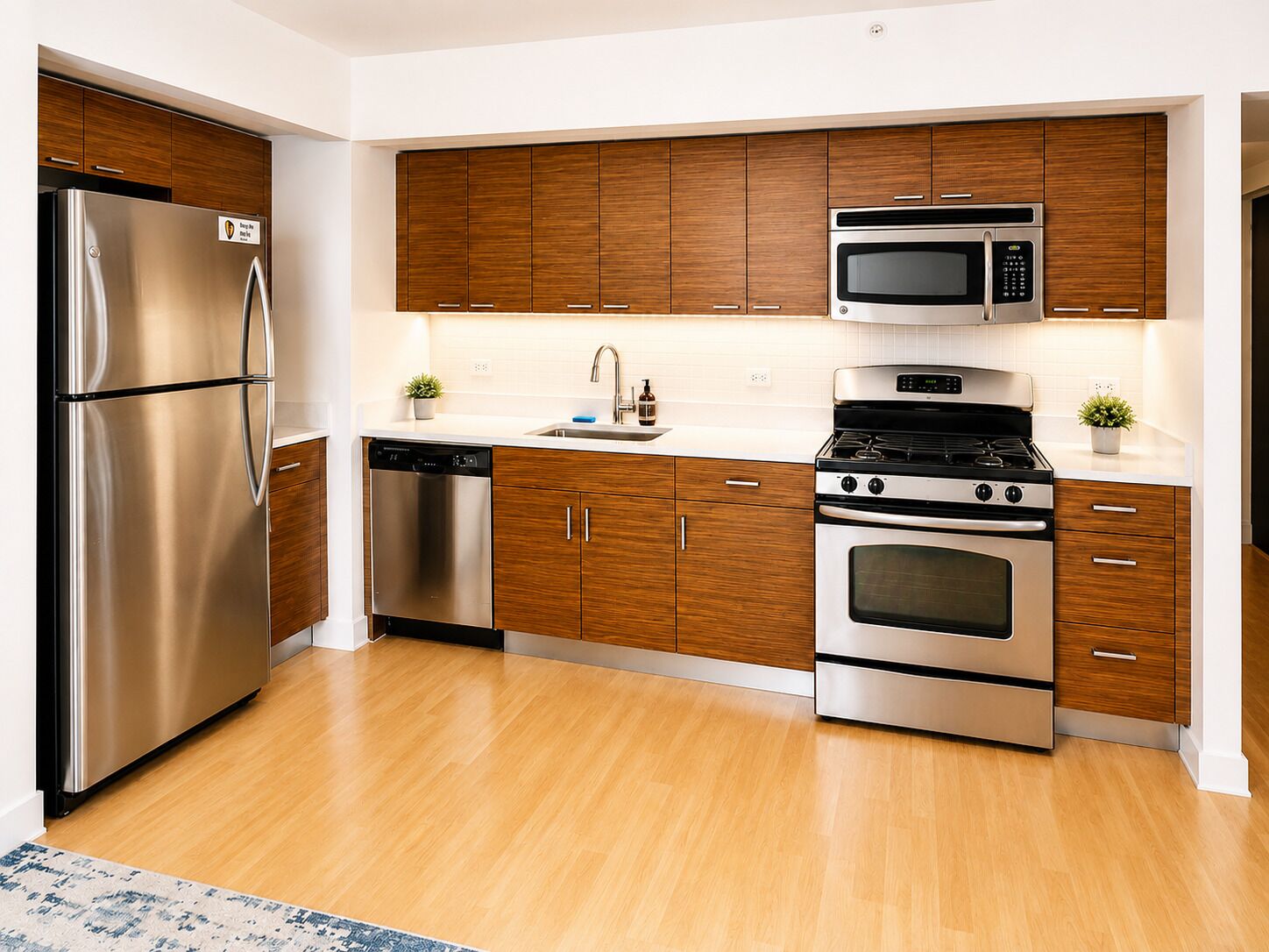 A modern kitchen with stainless steel appliances, wooden cabinets, and a tiled backsplash.