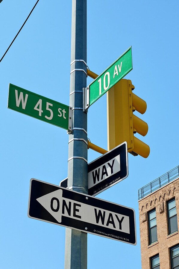 Street signs for W 45 st and 10 Av, a one-way sign, and a traffic light.