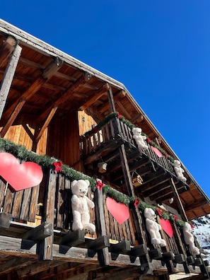 A wooden building with a balcony decorated with teddy bears and hearts.