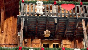 Un edificio de madera con un balcón decorado con ositos de peluche y corazones rojos.