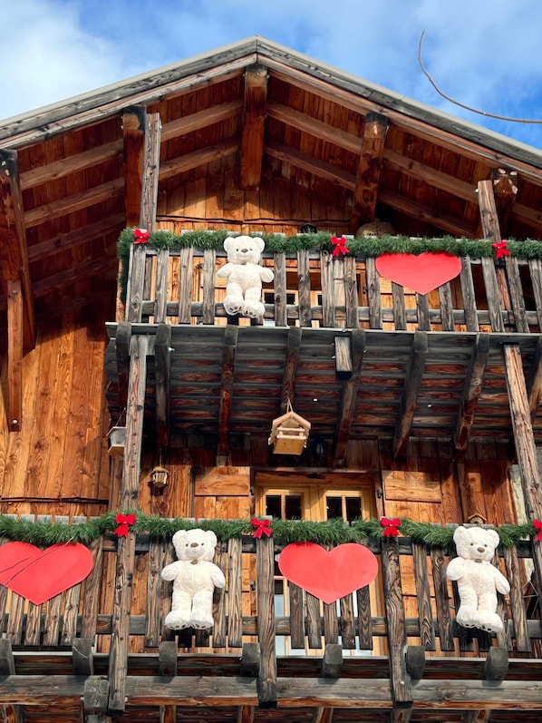 A wooden building with a balcony decorated with teddy bears and red hearts.