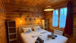 Un dormitorio de cabaña de madera con una cama, estanterías y una lámpara colgante.