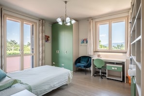 Une chambre à coucher comprenant un lit, un bureau, une chaise, une armoire et de grandes fenêtres.