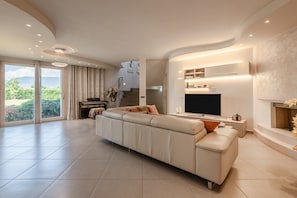 Un salon moderne avec un grand canapé, un téléviseur à écran plat et une cheminée.