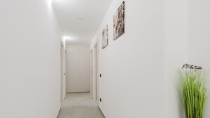 A hallway with white walls, a potted plant, and artwork. - Bed And Breakfast Champagneria 'Room 4' with Shared Terrace, Wi-Fi and Air Conditioning (Castelvetrano)