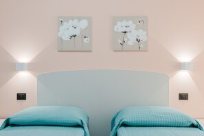 Ein Schlafzimmer mit zwei Betten, einem gewölbten Kopfteil und zwei Wandleuchten.