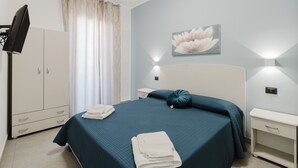 A bedroom with a bed, a wardrobe, a television, and a wall-mounted light fixture. - Bed and Breakfast Champagneria 'Room 1' with Shared Terrace, Wi-Fi and Air Conditioning (Castelvetrano)