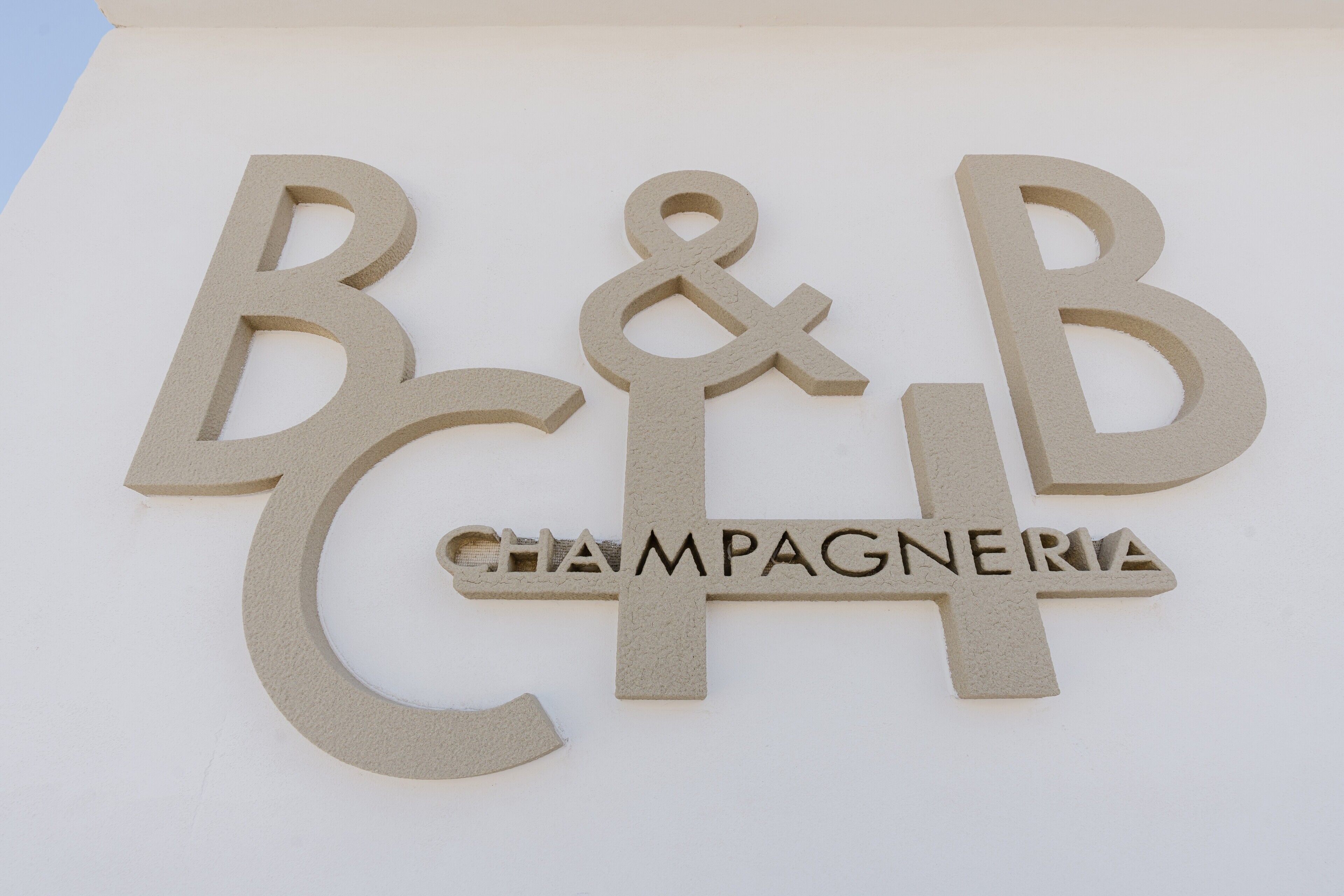 A sign with the letters 'B&B' and the word 'CHAMPAGNERIA' in a stylized font.