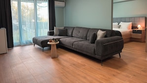 Ein modernes Wohnzimmer mit einem grauen Sofa, einem kleinen runden Tisch und einem Nachttisch mit einer Lampe.