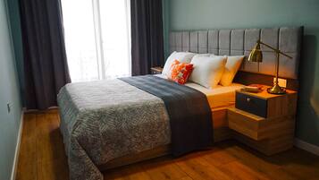 A neatly made bed with a patterned bedspread, a bedside lamp, and a nightstand with a drawer.