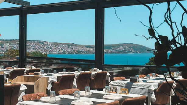 Ein Restaurant mit gedeckten Tischen mit Blick auf eine Küstenstadt.