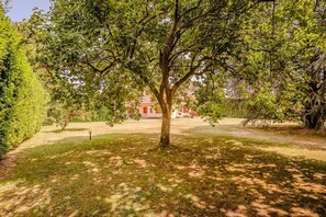 A tree-lined pathway leading to a building with a red facade. - Lesa Villas (Lesa)