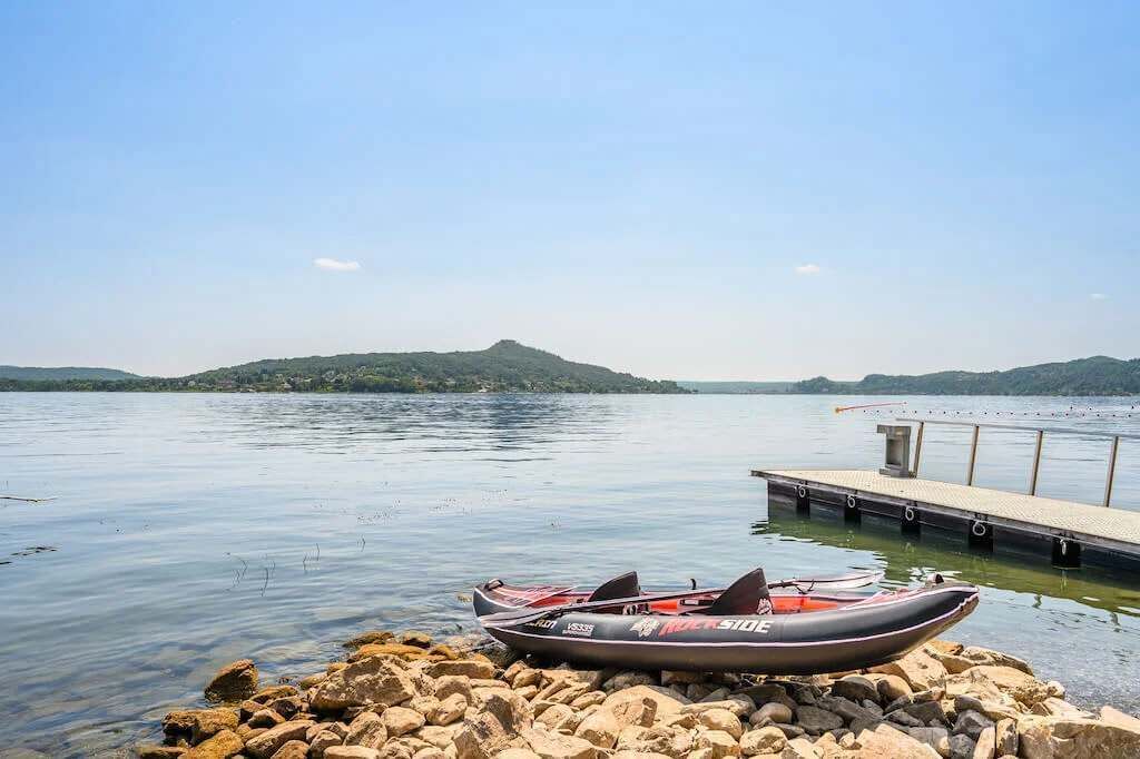 A calm lake with a rocky shore and a boat docked at a pier.