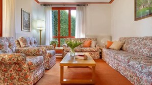 A living room with floral-patterned sofas, a wooden coffee table, and a window with curtains. - Lesa Villas (Lesa)