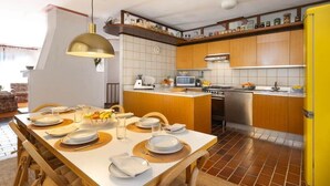 A modern kitchen with wooden cabinets, a central island, and a dining area set for six. - Lesa Villas (Lesa)