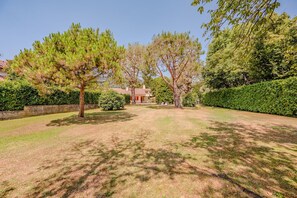 A residential property with a well-maintained lawn, mature trees, and a house in the background. - Lesa Villas (Lesa)